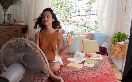 image of a girl sitting in front of a fan calming herself after the stress of summer classes